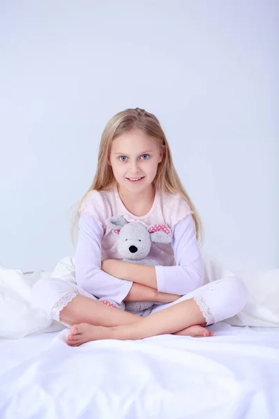 Маленькая девочка в спальне сидит на кровати. Маленькая девочка в пижаме и сидел на кровати — стоковое фото