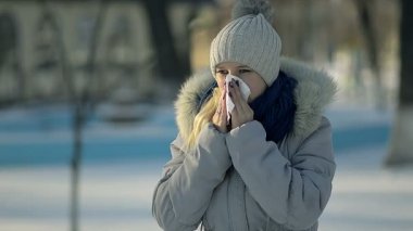 Закрыть вверх больная девушка дует нос в зимнем парке — стоковое видео