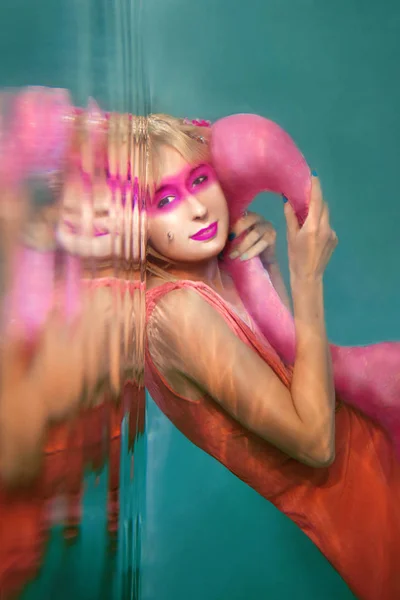 Портрет красивой блондинке с розовыми фламинго, летающие под водой в бассейне — стоковое фото
