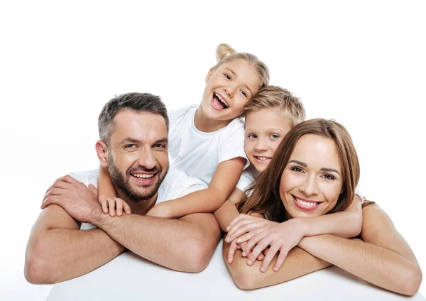 Улыбающаяся семья в белых футболках обниматься — стоковое фото