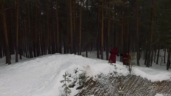Torchlight procession. Group of monks in hood robe walking along winter snow trail in forest. Footage. Group of monks in hood robe walking along winter snow trail in forest — стоковое фото