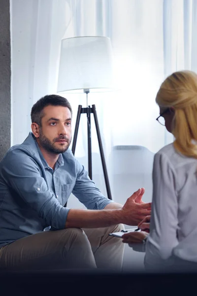 Man Gesturing Talking Female Counselor While She Writing Clipboard Office — стоковое фото