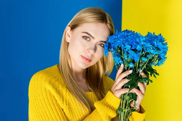 Attractive Young Girl Yellow Sweater Holding Blue Flowers Isolated Blue — стоковое фото