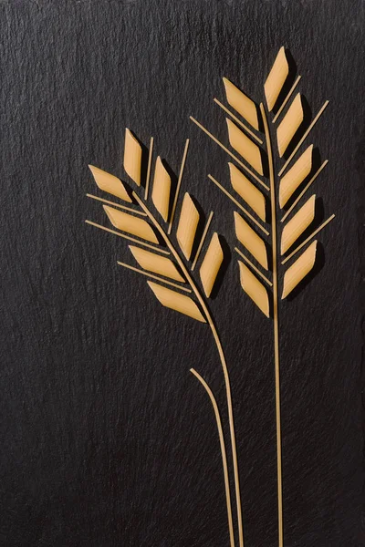 Вид Сверху Колосья Пшеницы Изготовлены Сырых Макаронных Изделий Черной Поверхности — стоковое фото