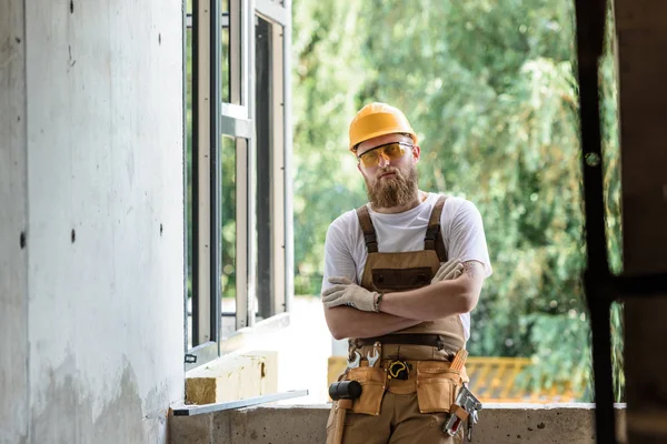 Smiling Builder Protective Googles Hardhat Standing Crossed Arms Construction Site — стоковое фото