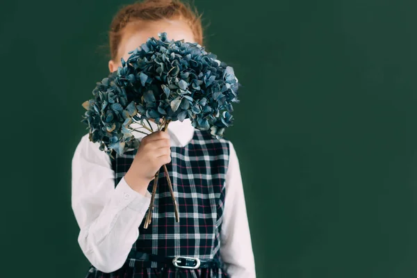 Beautiful Little Schoolgirl Holding Blue Flowers Twigs While Standing Chalkboard — стоковое фото