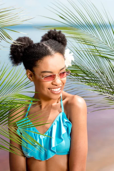 Smiling African American Woman Sunglasses Flower Hair Palm Leaves Front — стоковое фото