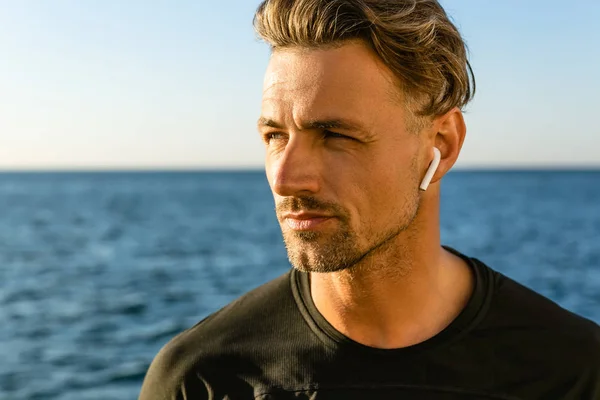 Close Portrait Handsome Adult Man Wireless Earphones Seashore Looking Away — стоковое фото