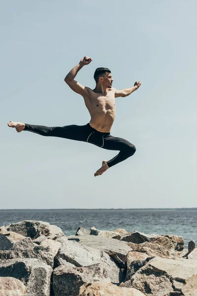 Athletic Shirtless Dancer Jumping Rocky Seashore — стоковое фото