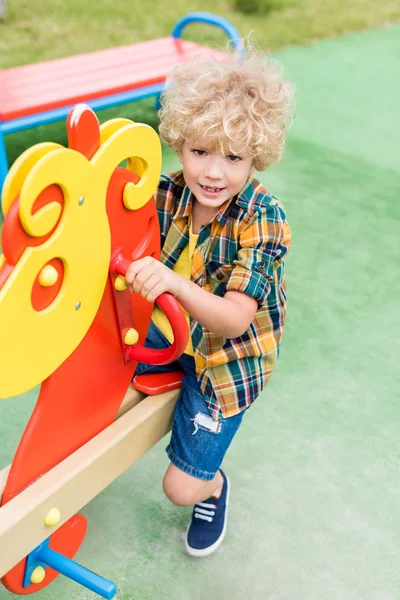 High Angle View Happy Curly Boy Riding Rocking Horse Playground Стоковое Фото