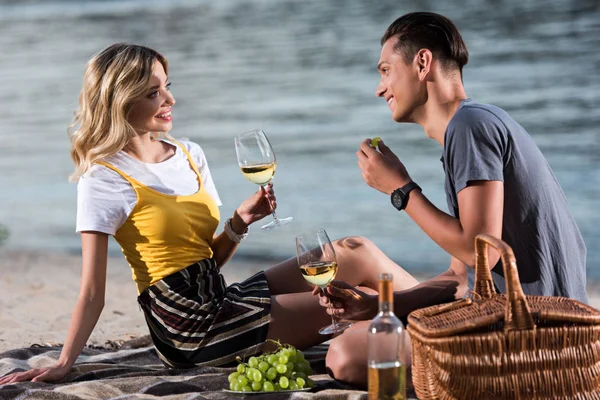 Smiling Young Couple Drinking Wine Eating Grapes Picnic River Beach — стоковое фото