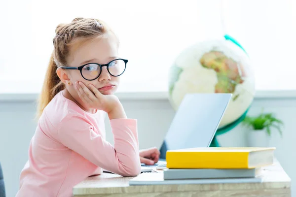 Bored Child Eyeglasses Looking Camera While Studying Laptop Books Стоковое Фото