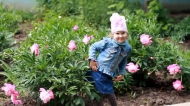 Child girl poses for a photo as a model in the garden with peonies. — стоковое видео