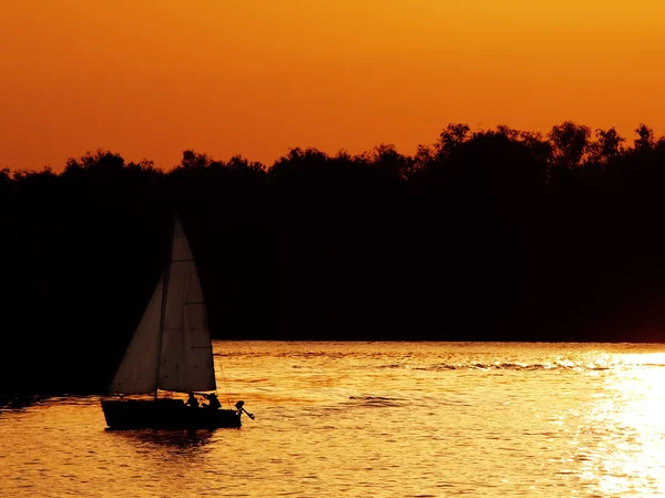 Парус лодки на реке на закате Лицензионные Стоковые Изображения
