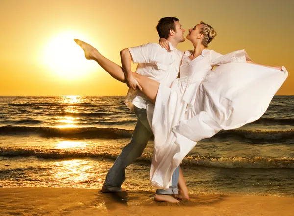 Красивая молодая пара танцует танго на пляж на закате — стоковое фото