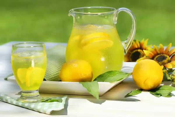 Кувшин прохладный лимонад с стеклом на столе — стоковое фото