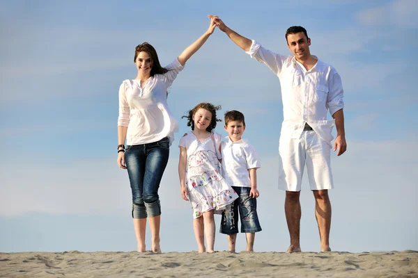 Семья на пляже, показывая домашний знак — стоковое фото