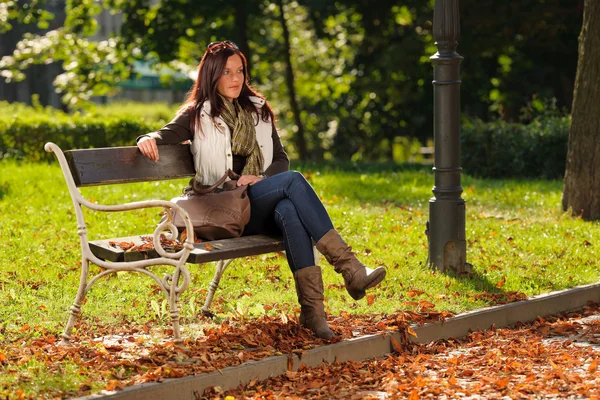 Осень красивая женщина сидеть на скамейке парка — стоковое фото