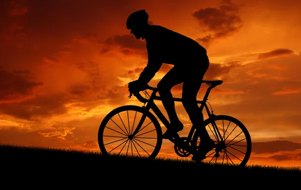 Велосипедист, езда на велосипеде по дороге на закате — стоковое фото