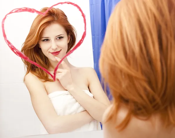 Рыжая девочка около отражает с сердцем в нем в ванной — стоковое фото