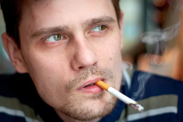 Среднего возраста человек курит сигарету в баре. Сосредоточиться на глазах — стоковое фото
