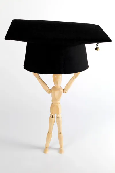 Деревянная фигурка, держащая академическую шапочку — стоковое фото