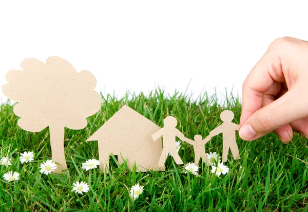 Рука держать бумаги вырезать семьи над свежей весенней зеленой травы — стоковое фото