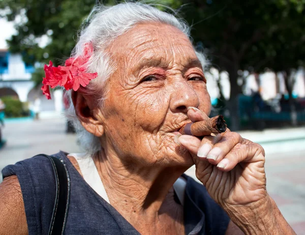Старые морщинистые женщина с сигары для некурящих красный цветок — стоковое фото