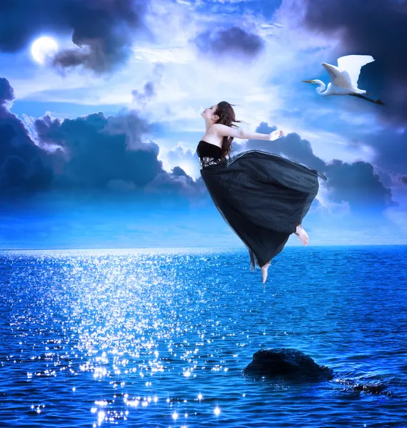 Красивая девочка прыгает в синий ночное небо — стоковое фото