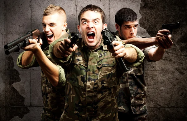 Трое солдат, направляющих оружие — стоковое фото