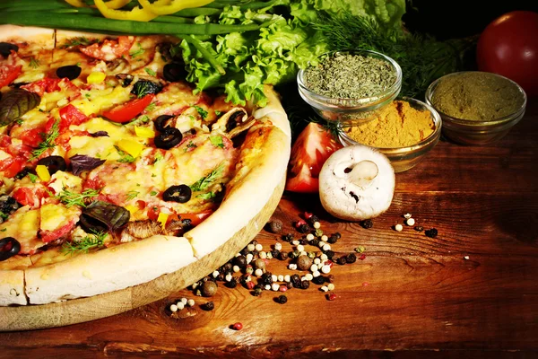 Вкусная пицца, овощи и специи на деревянный стол — стоковое фото
