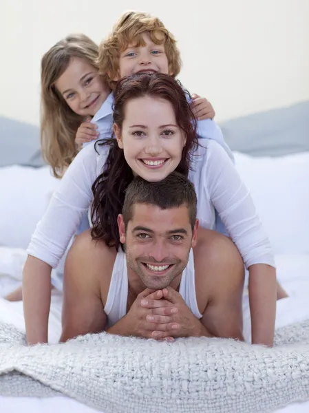 Портрет Счастливые родители и дети веселятся в постели — стоковое фото