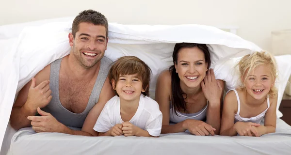 Родители и дети играют на кровати родителей — стоковое фото
