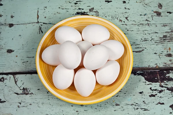 Белые яйца на желтой табличке — стоковое фото