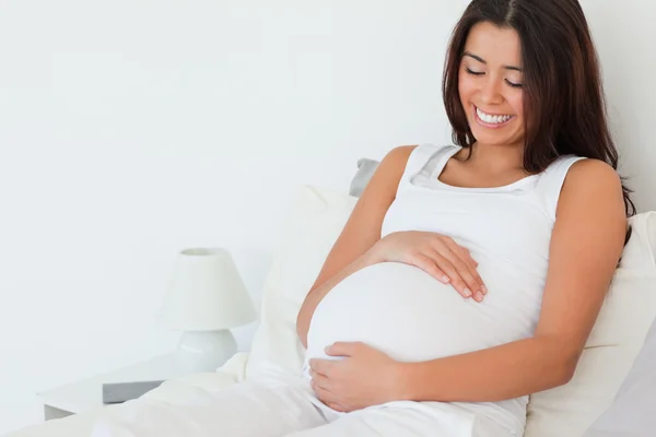 Великолепная беременная женщина позирует лежа на кровати — стоковое фото