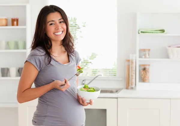 Привлекательная беременная женщина, держащаяся миску салата, стоя — стоковое фото