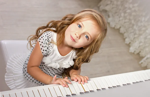 Красивая блондинка маленькая девочка в pretties сидит возле фортепиано — стоковое фото