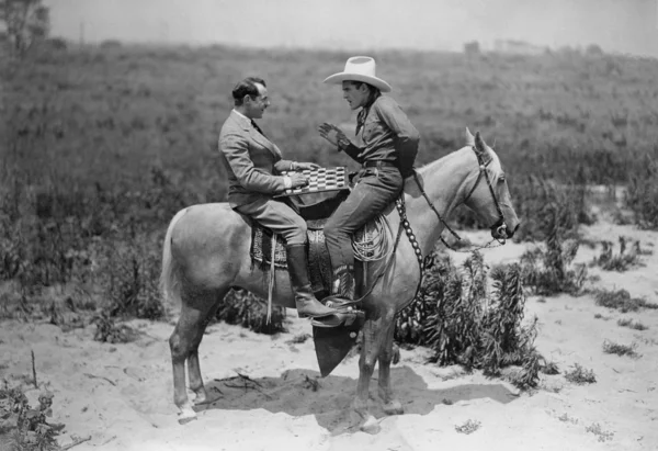 Ковбой и бизнесмен, играть в шашки на лошадях Лицензионные Стоковые Изображения