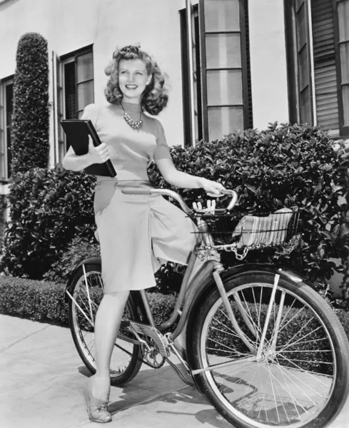 Женщина, сидящая на велосипеде с книгой в руках — стоковое фото